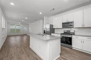 a kitchen with stainless steel appliances granite countertop a stove top oven a sink dishwasher and a microwave oven with wooden floor