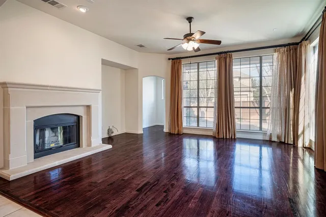 a view of an empty room with wooden floor fireplace and a window