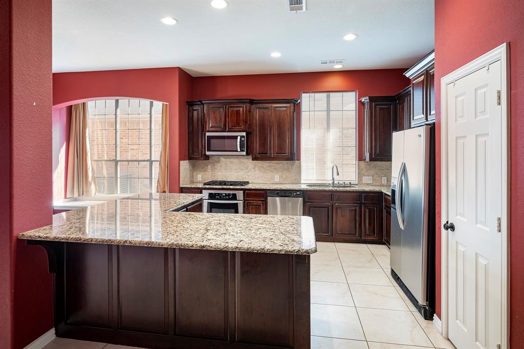 1138 Amy Drive Allen, TX 75013 - Photo 7 of 26 a kitchen with stainless steel appliances kitchen island granite countertop a refrigerator a stove and a sink with wooden cabinets