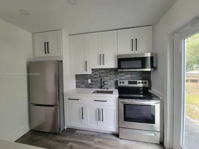 a kitchen with white cabinets and stainless steel appliances