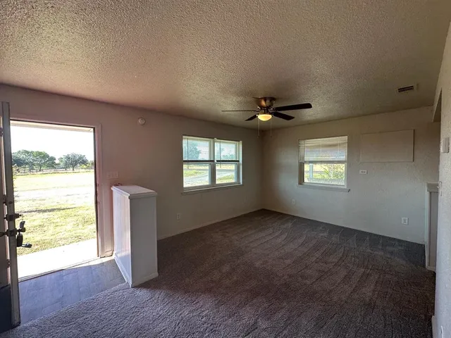 an empty room with windows and ceiling fan
