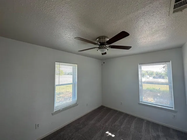 an empty room with windows and fan