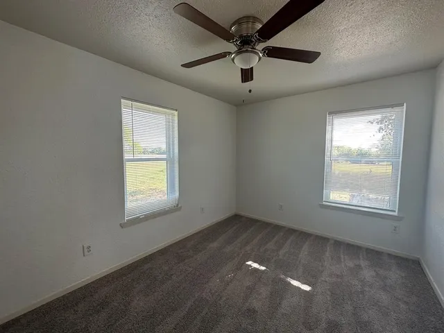 an empty room with a window and a fan