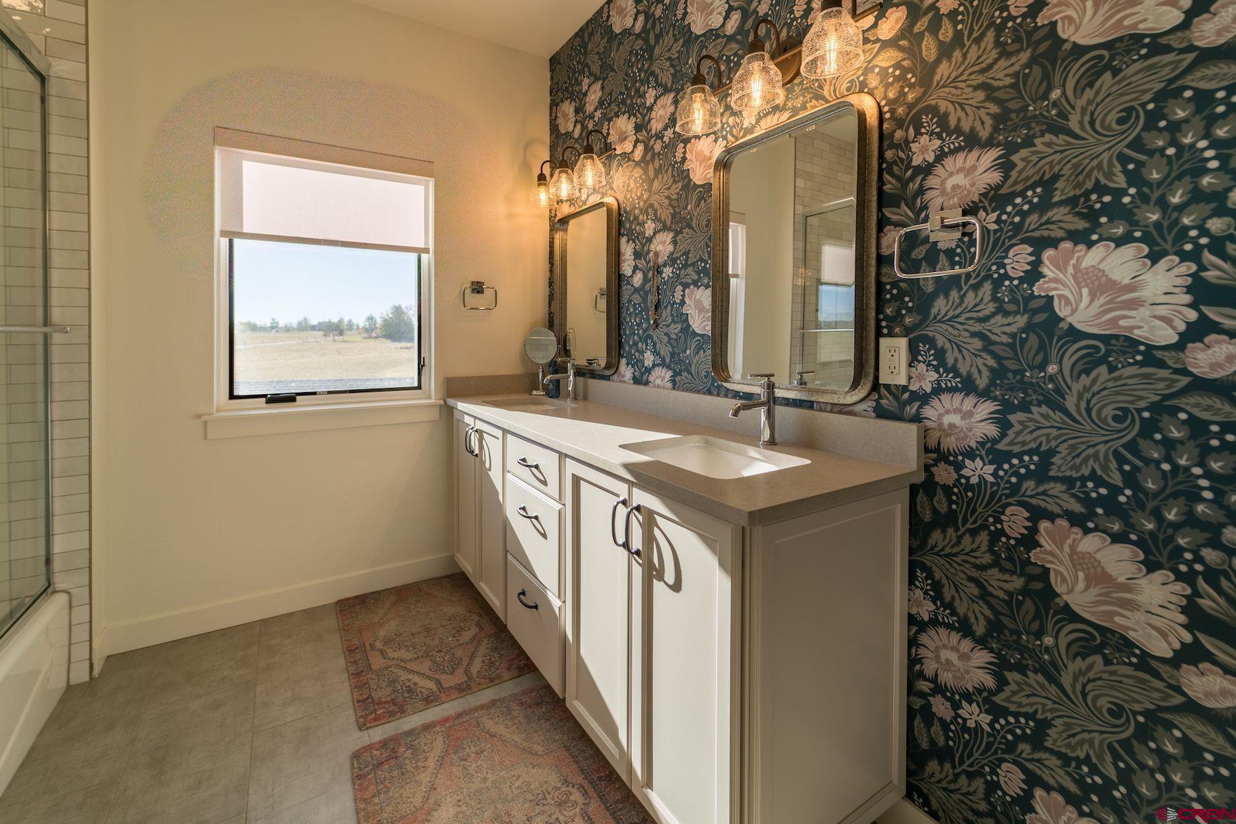 67 Range Road Durango, CO 81303 - Photo 22 of 34 a bathroom with a double vanity sink a mirror and a bathtub