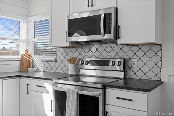 a kitchen with granite countertop white cabinets and white appliances