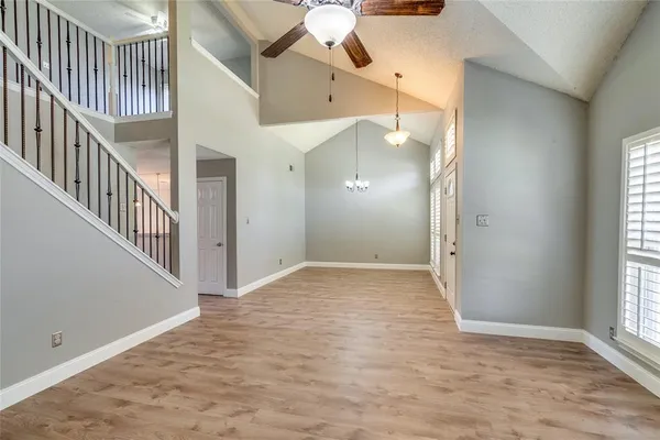 a view of an empty room with wooden floor and a fireplace