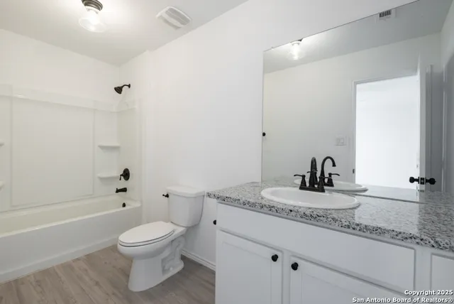 a bathroom with a granite countertop sink a toilet and a bathtub