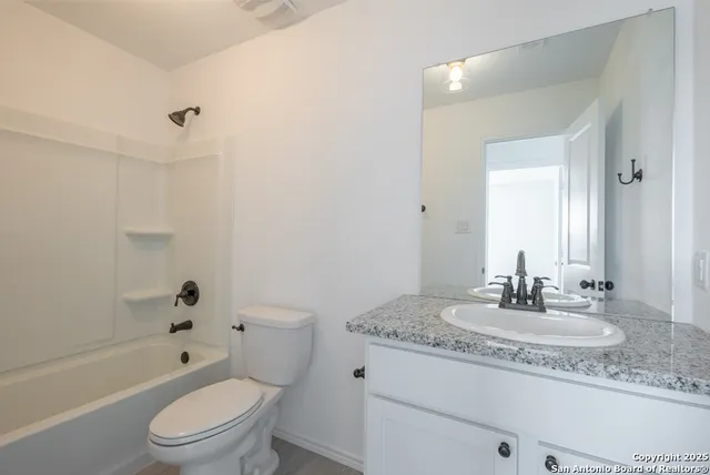 a bathroom with a granite countertop toilet a sink and a bathtub