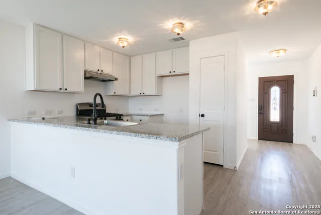 a kitchen with stainless steel appliances granite countertop a sink stove and white cabinets