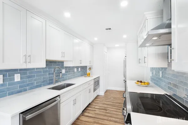 a large kitchen with stainless steel appliances a large counter top a stove and a sink