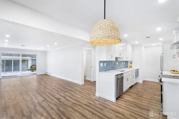 a kitchen with stainless steel appliances granite countertop a sink a stove and a wooden floors