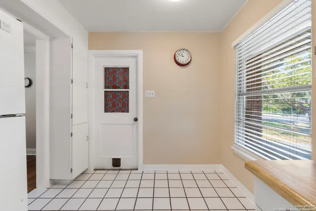 a view of an empty room with window and chandelier fan