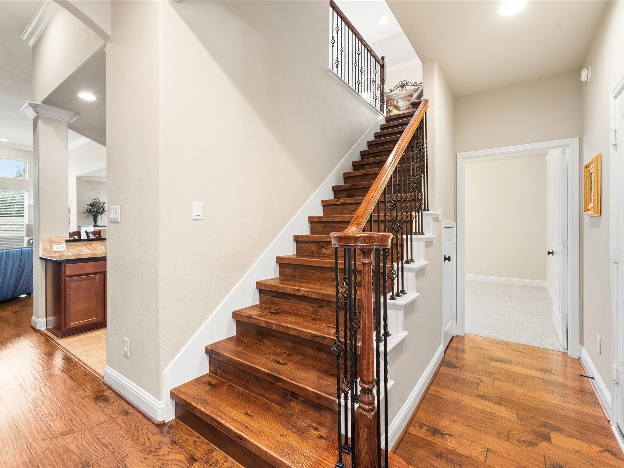 3907 Randle Ridge Court Fulshear, TX 77441 - Photo 26 of 46 This photo showcases a bright, inviting hallway with polished wood flooring and a classic staircase featuring elegant iron balusters. The area leads into a spacious, second floor game room/media room/full bath and a 4th full bedroom.