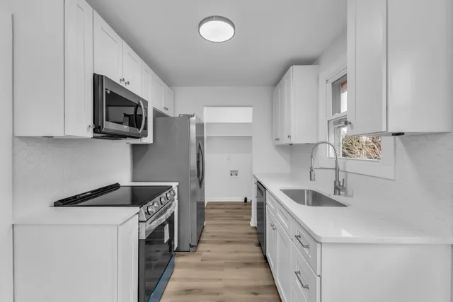 a kitchen with stainless steel appliances granite countertop a sink and a stove top oven with wooden floor