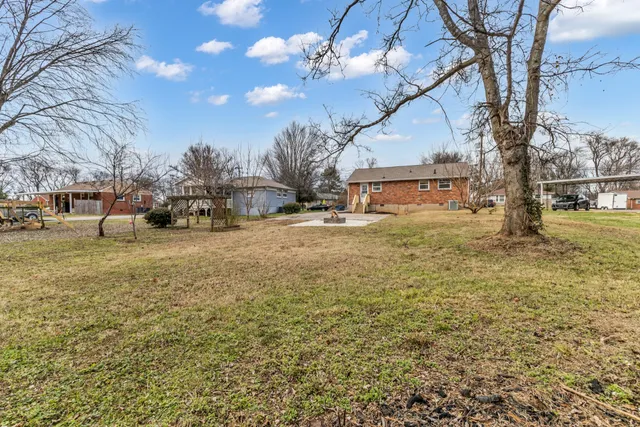 a backyard of a house with large trees and table