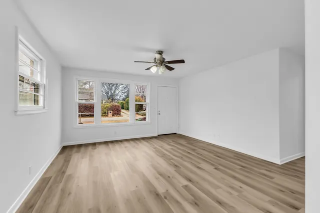 a view of an empty room with a window and wooden floor