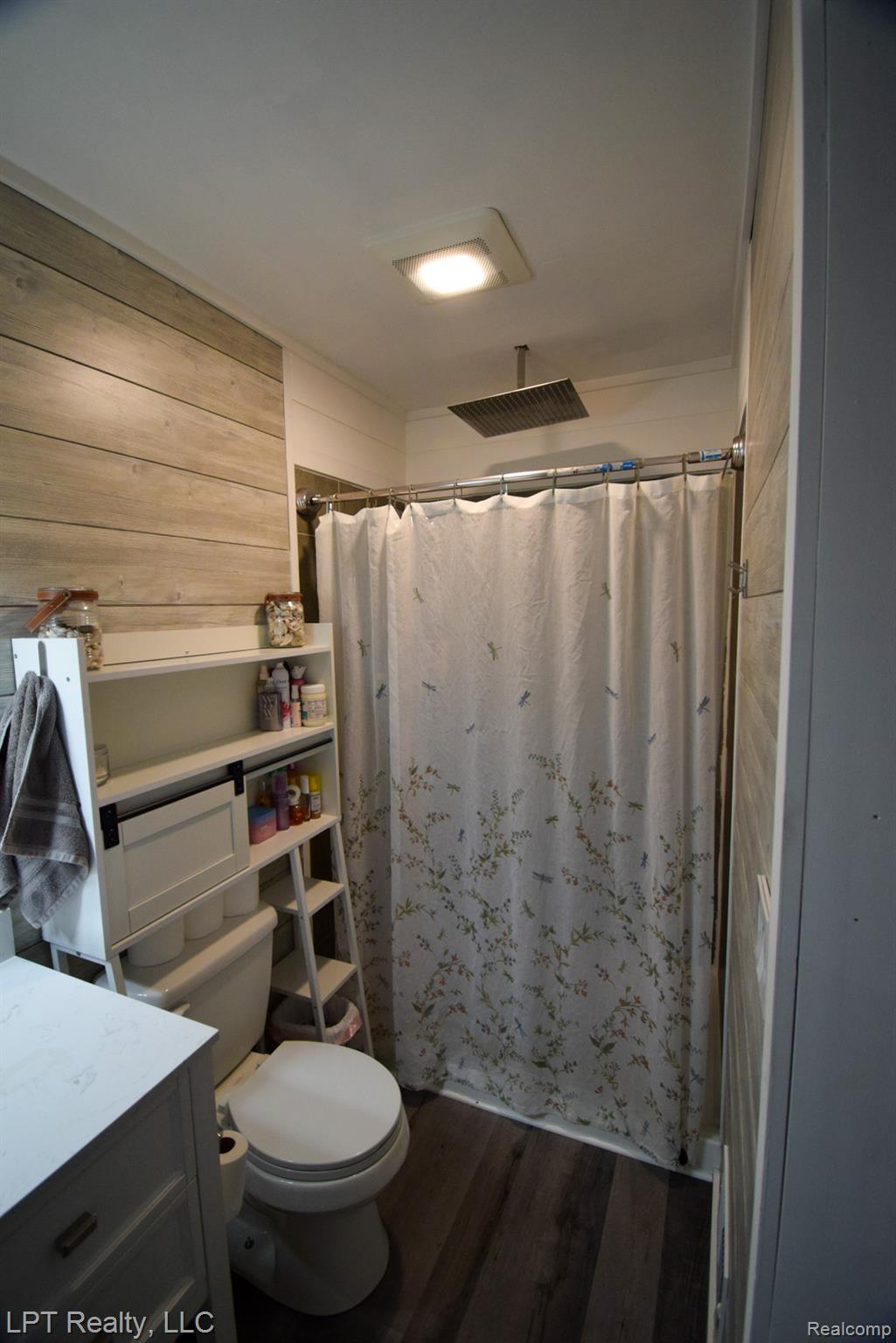 217 Nawakwa Road Rochester, MI 48307 - Photo 14 of 29 Bathroom featuring laminate wood finished floors, vanity, curtained shower, and wooden walls