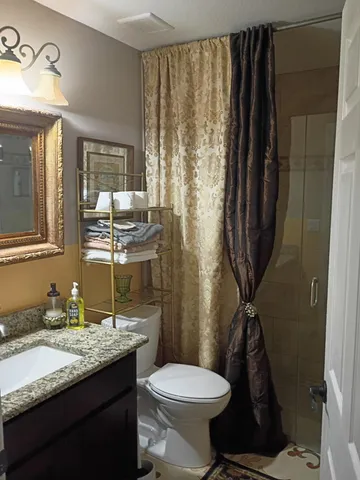 a bathroom with a granite countertop sink toilet and shower