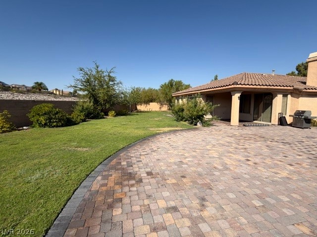 19 Mohansic Road Henderson, NV 89052 - Photo 25 of 30 A spacious paver patio adjoins a lush green lawn, offering ample outdoor entertaining space.