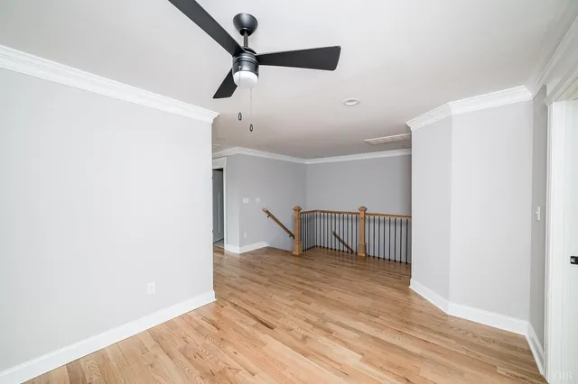 an empty room with ceiling fan and windows