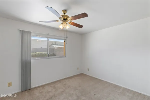 an empty room with a window and ceiling fan