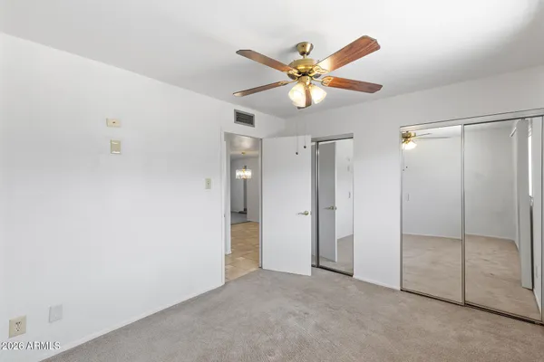an empty room with windows and fan