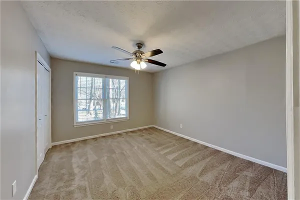 an empty room with chandelier fan and windows