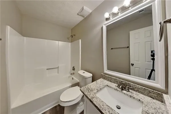 a bathroom with a granite countertop sink a toilet and a mirror