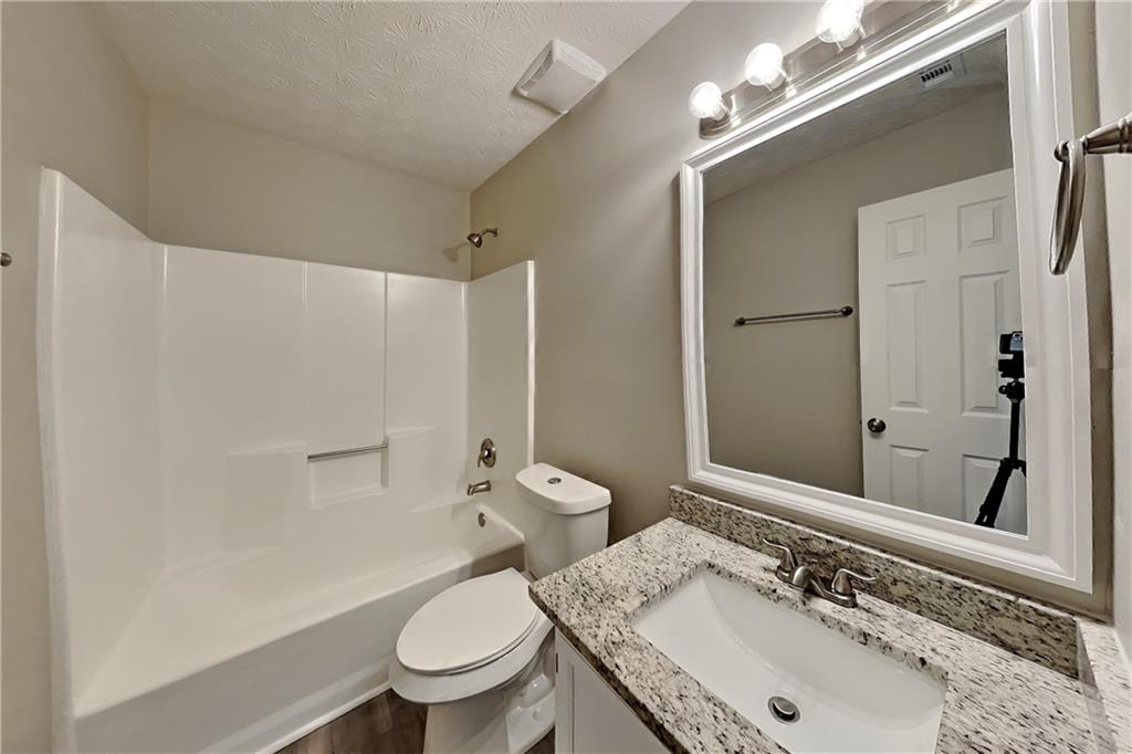 2705 Braemore Place Powder Springs, GA 30127 - Photo 13 of 18 a bathroom with a granite countertop sink a toilet and a mirror
