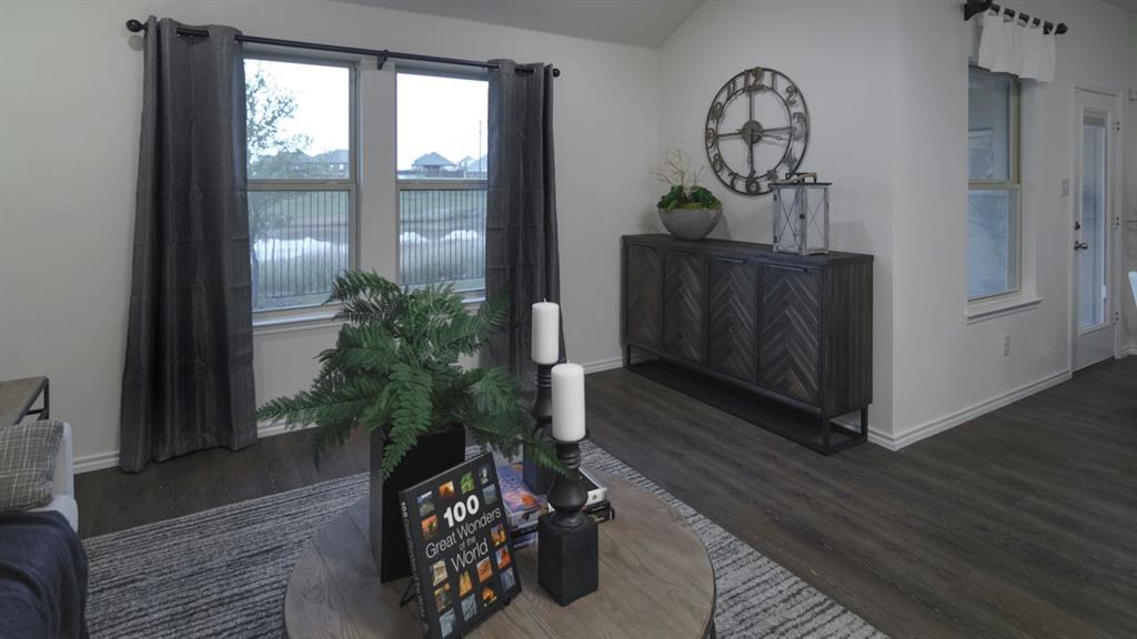 3100 Charleston Drive Ennis, TX 75119 - Photo 20 of 23 Spacious living area featuring wood-finish flooring, light neutral wall tones, and a pair of large windows with dark drapery panels