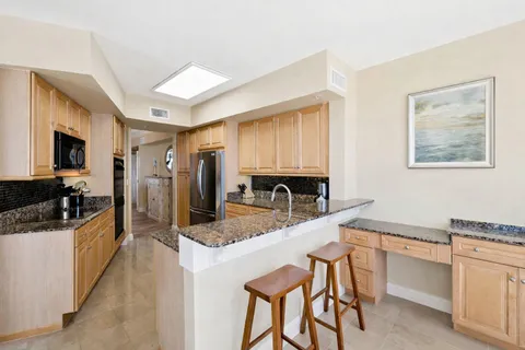 a kitchen with granite countertop kitchen island stainless steel appliances a sink stove top oven and granite counter tops