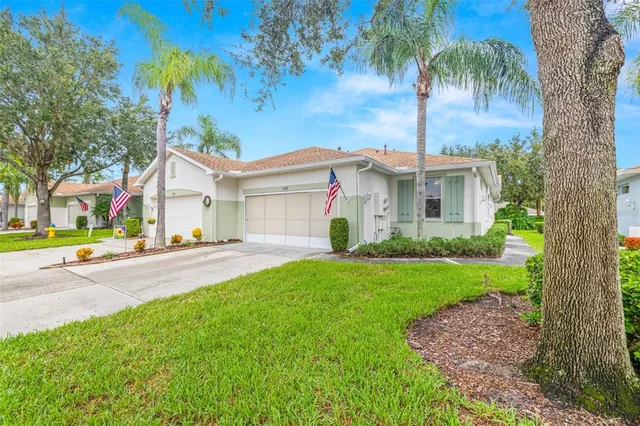 a view of a white house with a yard and palm trees