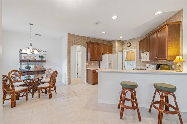a kitchen with stainless steel appliances a table chairs refrigerator and cabinets