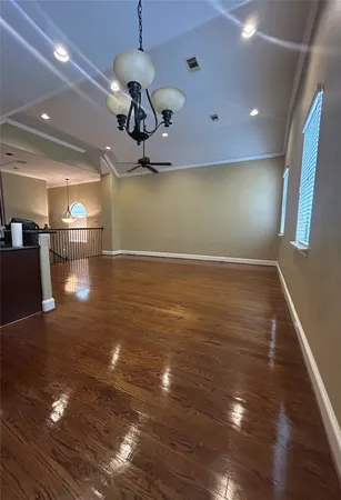 a view of a room with wooden floor ceiling fan and kitchen view