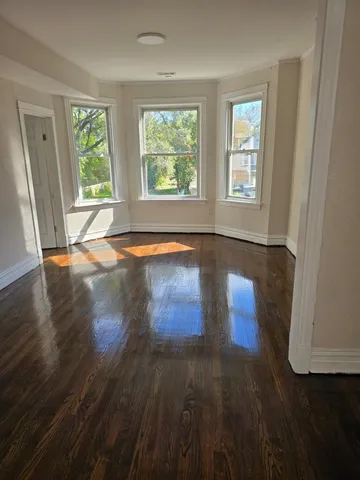 a view of an empty room with wooden floor and window