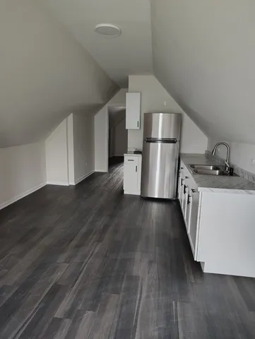 a kitchen with a sink a refrigerator and wooden floor