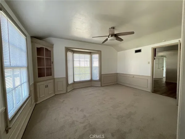 an empty room with windows and chandelier fan