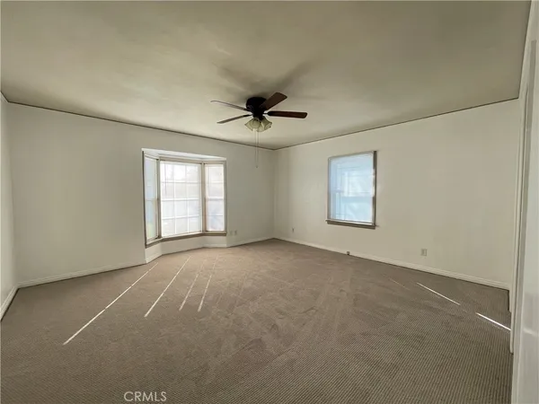 an empty room with windows and ceiling fan