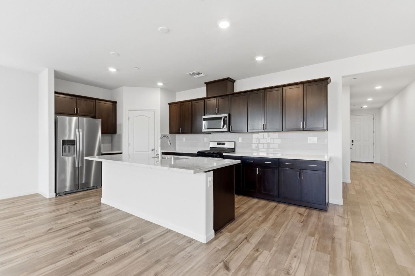 331 Lolly Way Los Banos, CA 93635 - Photo 20 of 31 a large kitchen with stainless steel appliances kitchen island granite countertop a stove and a wooden floors
