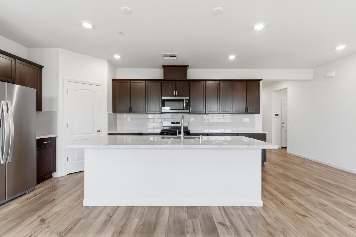 331 Lolly Way Los Banos, CA 93635 - Photo 23 of 31 a large kitchen with stainless steel appliances granite countertop a stove a refrigerator a sink a microwave and wooden floor