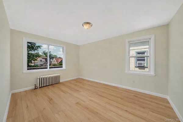 a view of an empty room with window and hardwood floor