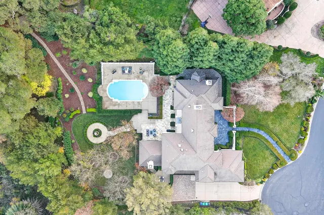 an aerial view of a house with a swimming pool a yard and a large tree