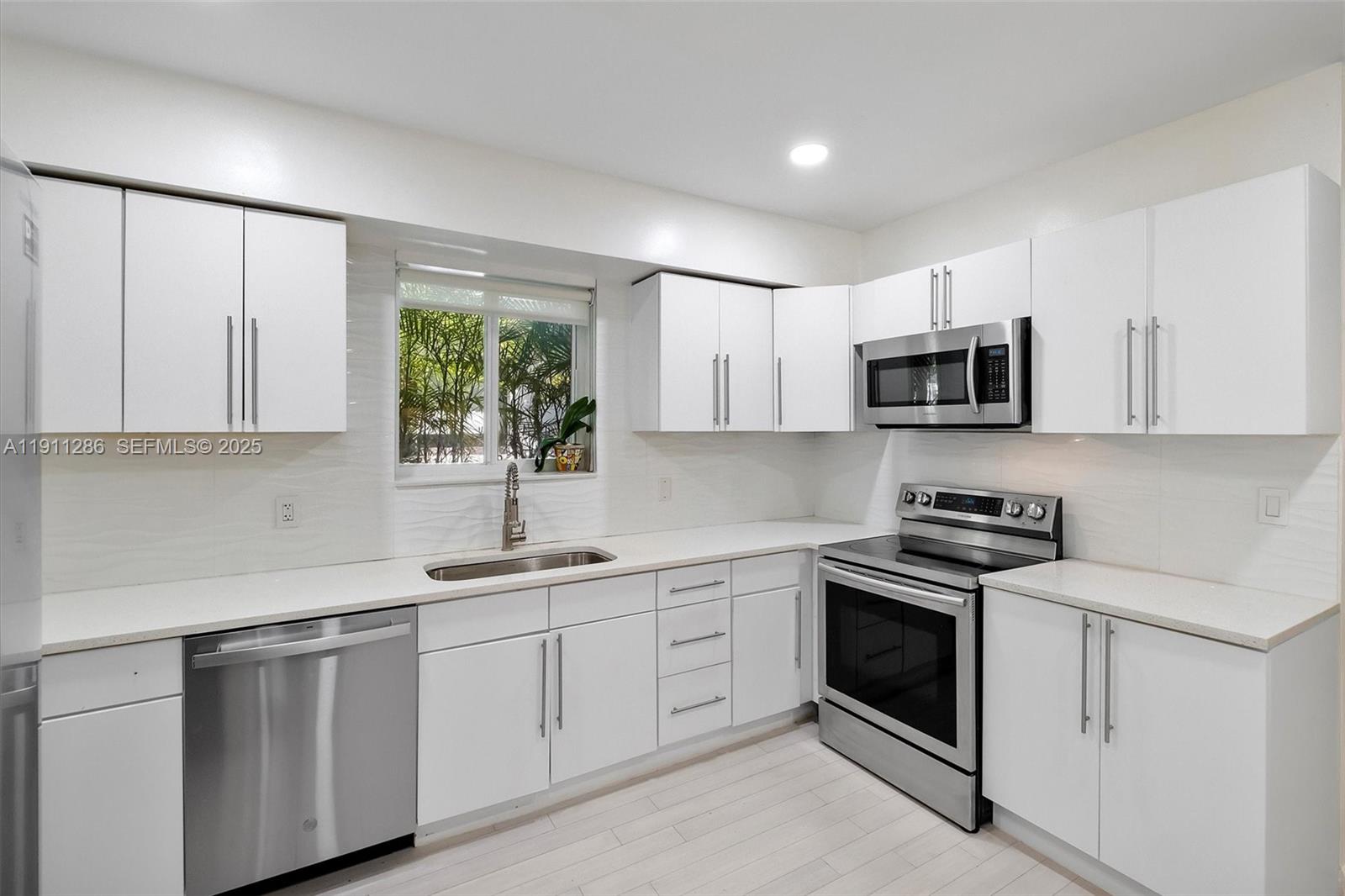 9049 Dickens Avenue Surfside, FL 33154 - Photo 12 of 34 a kitchen with white cabinets appliances and a window