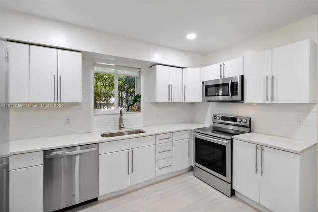 a kitchen with white cabinets appliances and a window