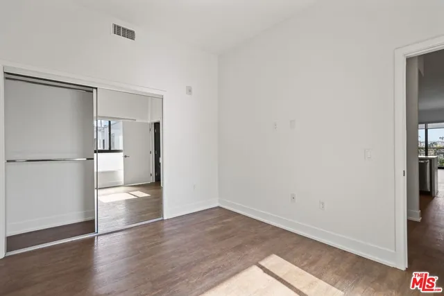 a view of empty room with wooden floor and a refrigerator