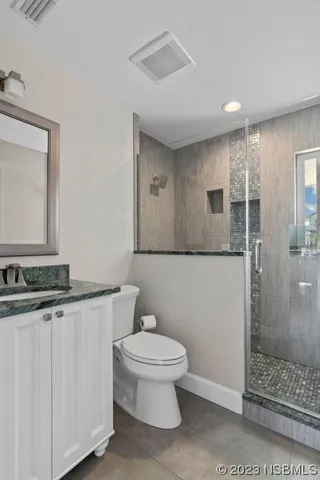a bathroom with a granite countertop sink a toilet a mirror and shower