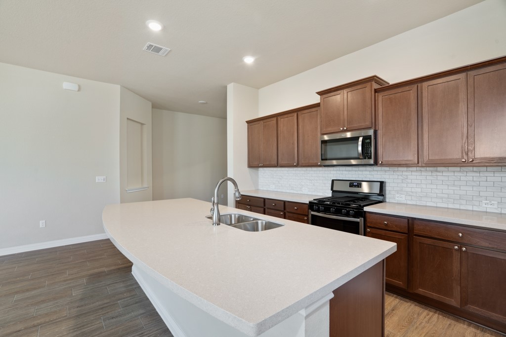 8202 Dampton Lane Austin, TX 78744 - Photo 7 of 25 a kitchen with a sink a stove a microwave and cabinets