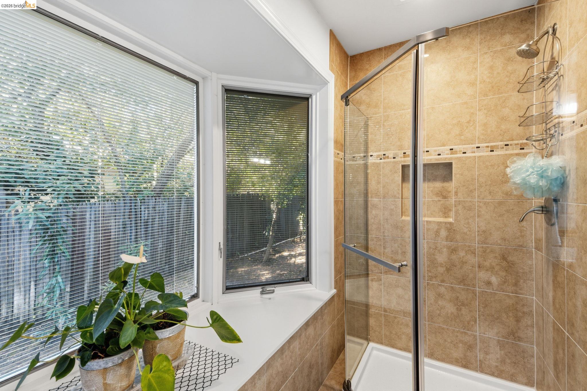 5075 Alhambra Valley Road Martinez, CA 94553 - Photo 25 of 68 Walk-in shower with glass enclosure, tiled walls featuring decorative accent border, and a built-in shower niche