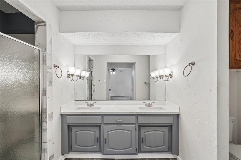 1600 South Timber Court Benbrook, TX 76126 - Photo 21 of 30 Dual vanity featuring undermount sinks, a light-toned countertop, and grey cabinetry