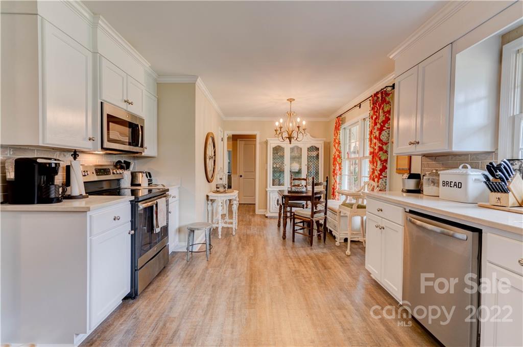 509 Roy Eaker Road Cherryville, NC 28021 - Photo 18 of 43 a kitchen with stainless steel appliances a refrigerator a stove top oven a sink dishwasher and white cabinets with wooden floor